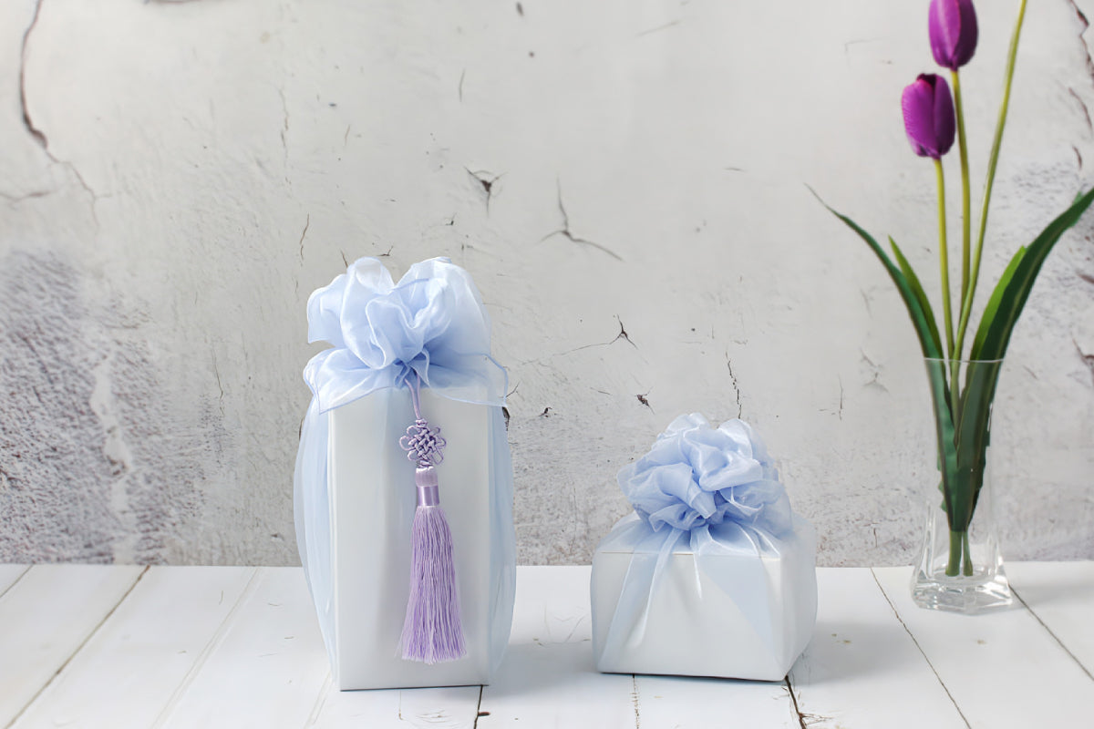 two quadrangle boxes wrapped with red and pink color Bojagi.