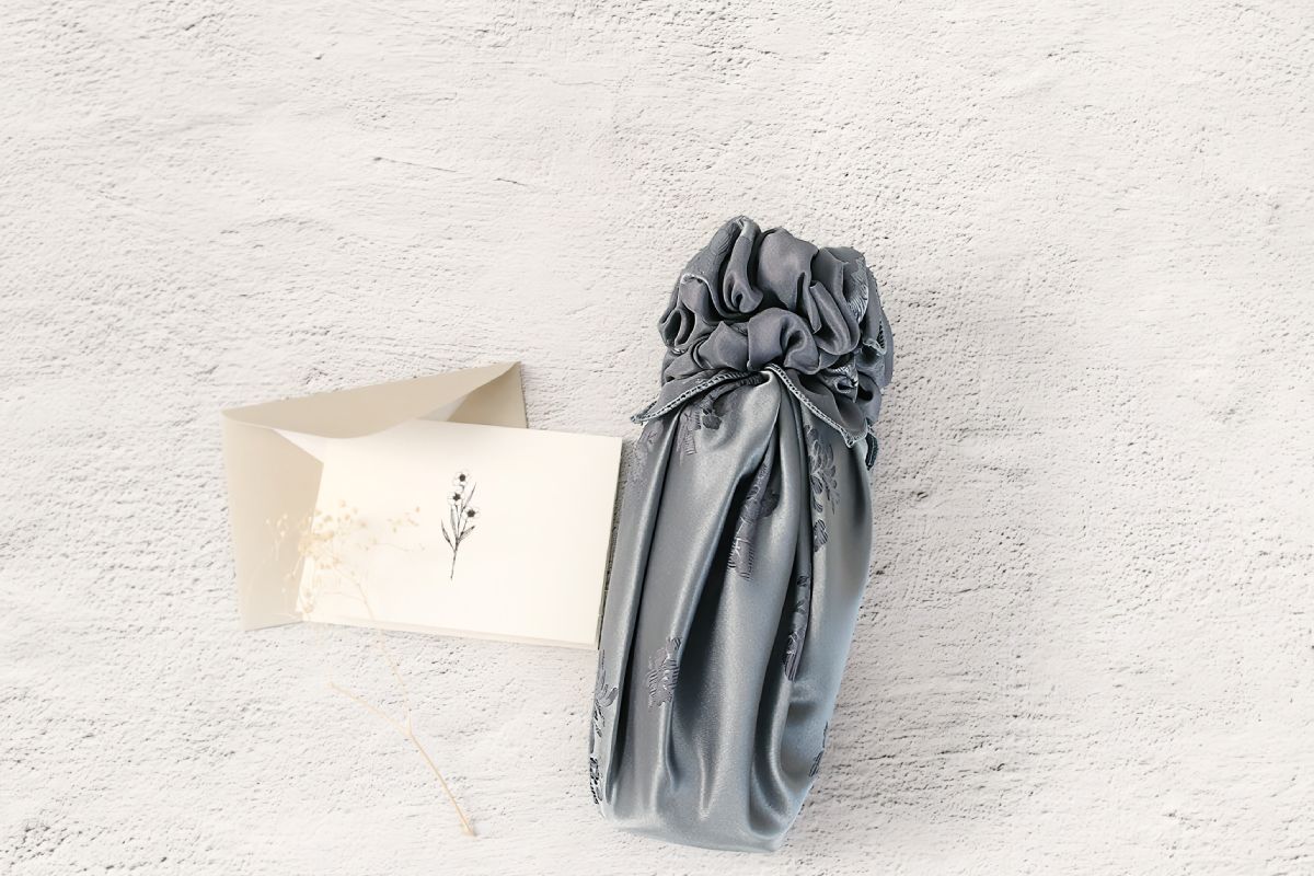 a bottle of wine wrapped with gray color see through fabric wrap(Bojagi).